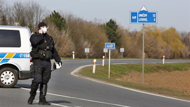 Policisté hlídají vjezd do uzavené oblasti.