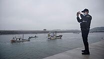 Policista v Jin Korei si nat lod ryb s banery proti japonskmu plnu...