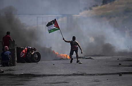 Demonstrant mv palestinskou vlajkou bhem stet s izraelskmi silami na...