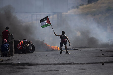 Demonstrant mává palestinskou vlajkou během střetů s izraelskými silami na...