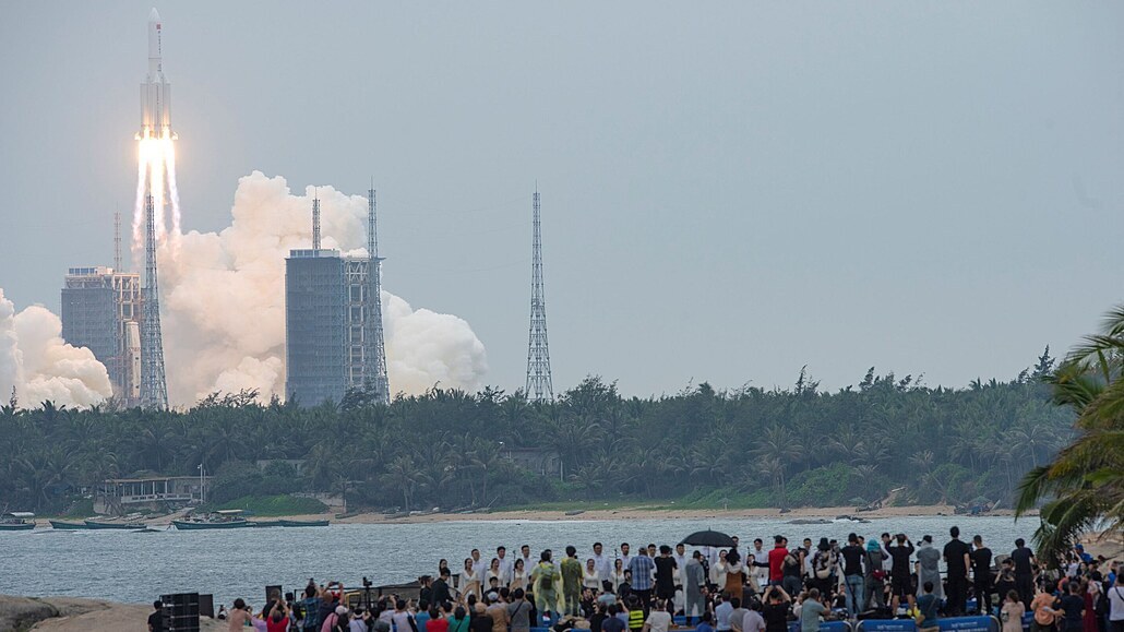 Lidé na pláži v čínské provincii Chaj-nan sledují start rakety Dlouhý pochod 5B.