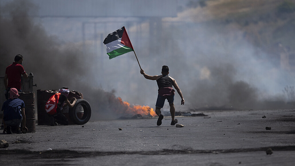Demonstrant mává palestinskou vlajkou během střetů s izraelskými silami na...