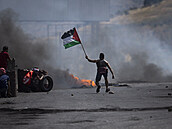 Demonstrant mává palestinskou vlajkou bhem stet s izraelskými silami na...