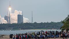 Lidé na plái v ínské provincii Chaj-nan sledují start rakety Dlouhý pochod 5B.