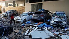 Kusy rozbombardovaného palestinského domu poničili v ulici stojící automobily.