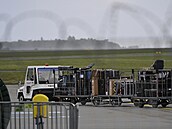 Letitní zamstnanec odváí vozíky se zavazadly k leteckému speciálu z Moskvy,...