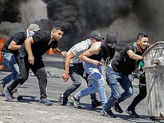 Protestujc Palestinci se kryj ped izraelskm vojskem.