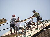 Dobrovolníci-profíci staví novou stechu rodinného domku.