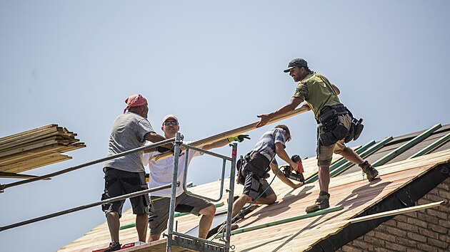 Dobrovolníci-profíci staví novou st�echu rodinného domku.