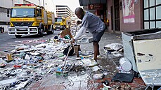 Dobrovolník pomáhá uklízet nepořádek po výtržnostech. Nepokoje v Jihoafrické...