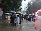 Lidé se v ín bhem záplav brodí vodou