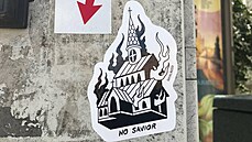 Nálepka s hořícím katolickým kostelem na sloupu na náměstí Jana Palacha v...