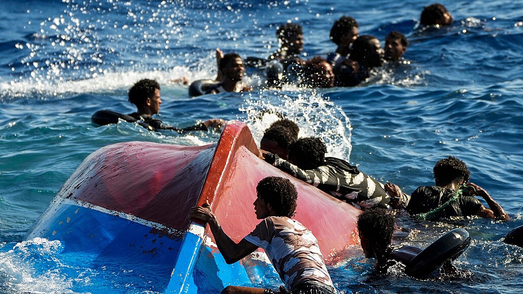 Na snímku z loňského srpna plavou uprchlíci kolem loďky, jež se s nimi převrhla...