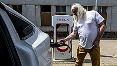 Řidič připojuje elektromobil Tesla k nabíječce v dobíjecí stanici v centru...