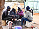 Migranti ze subsaharské Afriky v Tunisku sedí kolem improvizovaného ohn.