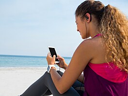 Mladá dívka pouívá mobilní telefon na plái u moe.