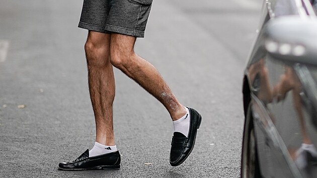 PARIS, FRANCE - JUNE 25: A guest wears black shoes, shorts, and a blue and...