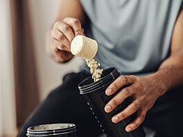 Mu� sypající si protein do shakeru.