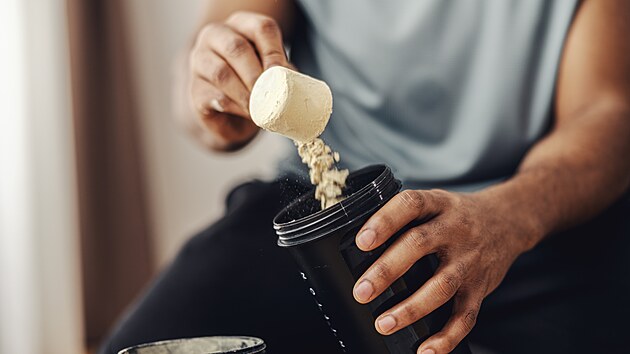 Mu� sypající si protein do shakeru.