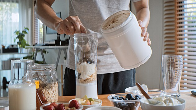 Mladý mu� si p�ipravuje proteinový nápoj s ovocem a cereáliemi pomocí mixéru....