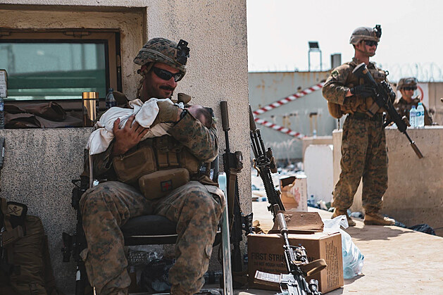 Příslušník americké námořní pěchoty tiší afghánského kojence během čekání na...