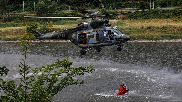 Armádní vrtulník Sokol nabírá vodu do bambi vaku během lesního požáru v Národním parku České Švýcarsko