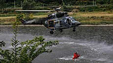 Armádní vrtulník Sokol nabírá vodu do bambi vaku během lesního požáru v...